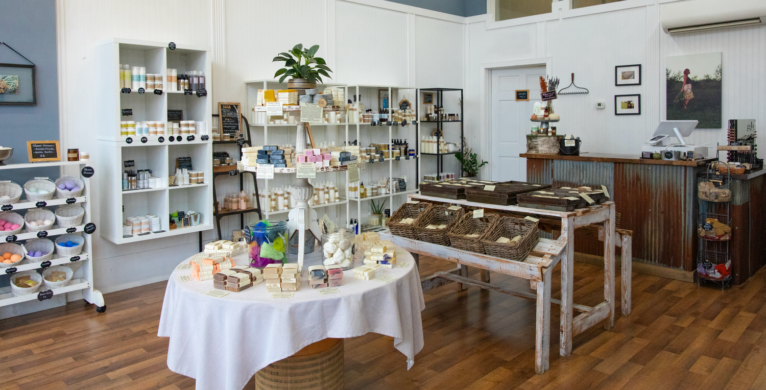 A floor view of a Modern Roots Minnesota location. Wall shelves and center tables are full of hand made soap bars and other clean, natural & non-toxic skincare products for holistic skin care